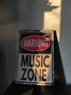 a sign that is sitting on top of a table next to a wall with the words warning music zone painted on it