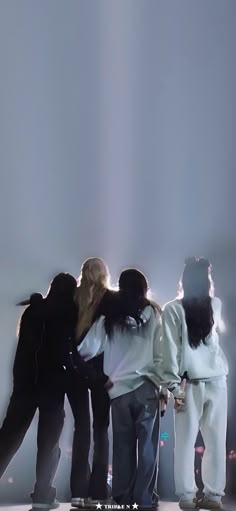 four people are standing on their skateboards in front of the light from behind them