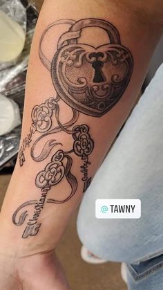 a person with a tattoo on their arm holding a heart shaped lock and key in the middle