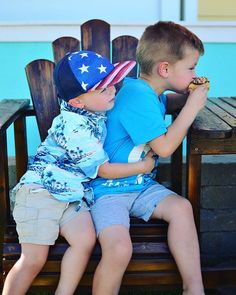 two young boys sitting on a bench eating donuts