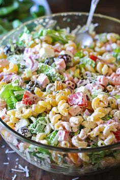 a salad in a glass bowl with dressing being drizzled on it's side