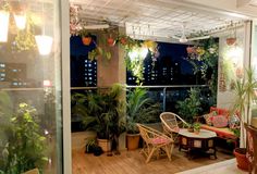 a balcony with potted plants and wicker furniture on the wooden floor next to glass doors