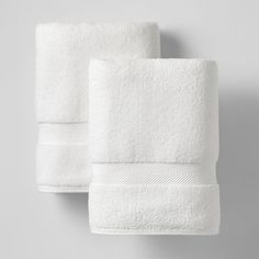 two white towels hanging on the wall next to each other, one folded in half