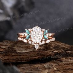 an engagement ring with turquoise and white stones on top of a wooden log in front of a black background