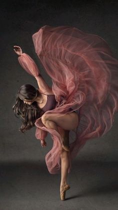 a woman in a pink dress is dancing with her arms spread out and legs bent