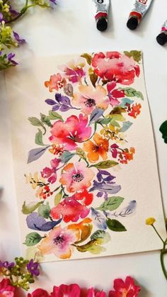 watercolor flowers on paper next to markers and pens