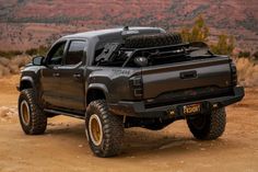 a black truck parked on top of a dirt field