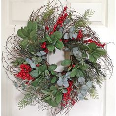 a wreath with red berries and greenery hangs on the front door's white paneled door