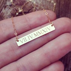 a person is holding a gold necklace with the word viv mmv on it