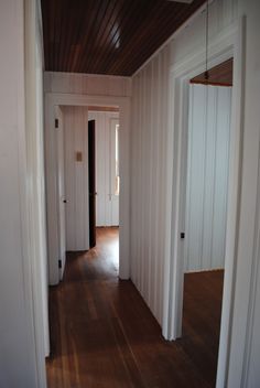 an empty room with wooden floors and white walls, is seen in this image from the doorway