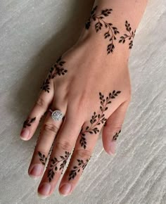 a woman's hand with black henna tattoos on her left wrist and fingers