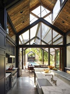 an open kitchen and dining area with large windows on the ceiling, along with stainless steel appliances