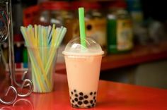 a drink sitting on top of a table next to a cup with a straw in it