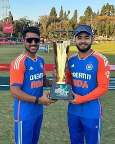 two men standing next to each other holding a trophy