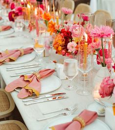 the table is set with pink and orange flowers