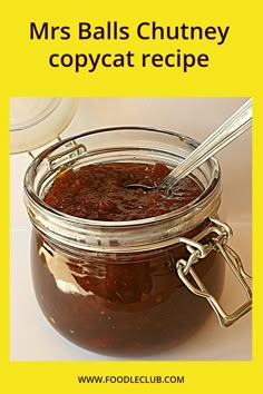 a jar filled with lots of food sitting on top of a white table next to a spoon