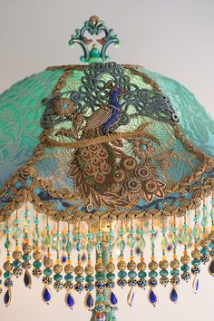 a green lamp shade with peacocks and beads hanging from it