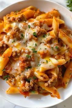 a white plate topped with pasta covered in meat and cheese on top of a table