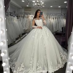 a woman taking a selfie in front of a mirror wearing a white wedding dress