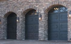 three black garage doors in front of a brick building with arched doorways on each side