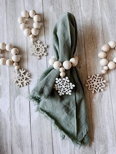 a green scarf with snowflakes on it next to some beads and necklaces