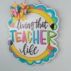 a sign that says living that teacher life hanging on a wall with a ribbon around it