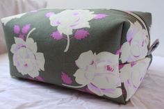 a floral print bag sitting on top of a bed