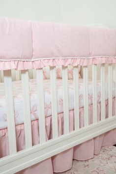 a baby crib with pink and white bedding on the bottom row, next to a carpeted floor