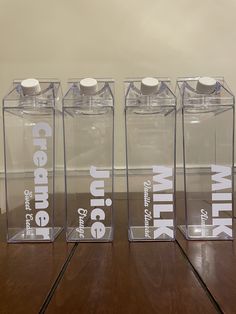 three clear bottles with white caps sitting on a wooden table