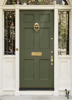 a green front door with two windows and a gold handle on the bottom part of the door