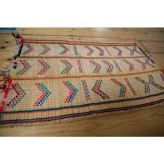 an old rug is laying on the floor next to a wooden floor with a blue and red stripe