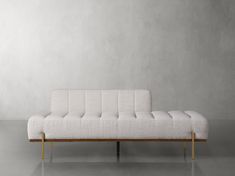 a white couch sitting on top of a metal frame in front of a gray wall