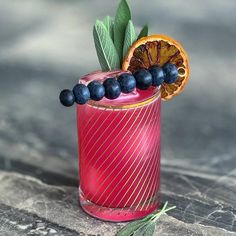 an orange and blueberry cocktail garnished with leaves