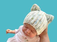 a baby wearing a crocheted hat with a cat ears on it's head