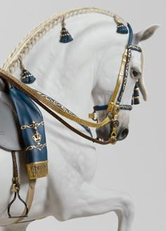 a white horse with blue and gold bridle on it's back legs