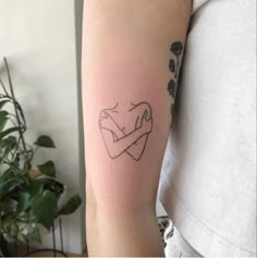 a woman's arm with a tattoo on it that has an outline of a hugging couple