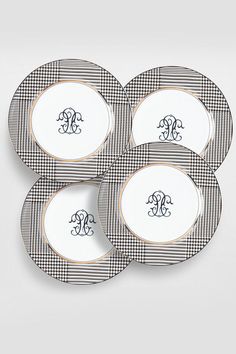 four black and white plates with monogrammed letters on them, all in the same pattern