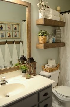 a white toilet sitting under a bathroom mirror next to a sink and a shower curtain