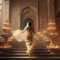 a woman in a white dress is walking down some stairs with lit candles around her