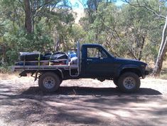 a pick up truck parked on the side of a dirt road next to some trees