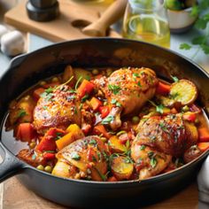 chicken and vegetable stew in a skillet on a cutting board with utensils