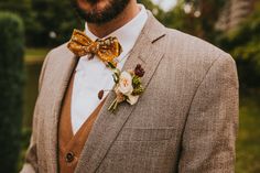 a man in a suit and bow tie is wearing a flower boutonniere