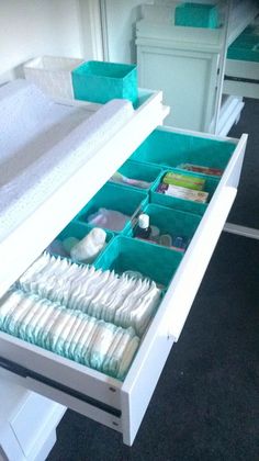 an open drawer in a bed room with folded towels and diapers on the bottom shelf