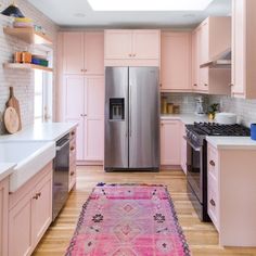 a kitchen with pink cabinets and an area rug on the floor in front of the refrigerator