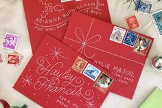 three red envelopes with stamps on them sitting next to christmas decorations and other items