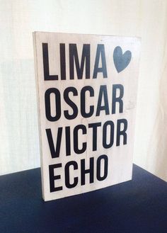 a wooden sign that says lima oscar victory echo on the side of a blue table