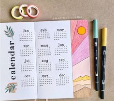 an open calendar book next to some scissors and markers