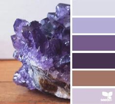 a rock with purple and brown colors on it, sitting on a wooden table next to a white wall