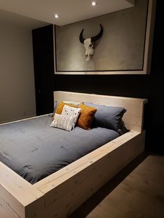 a bed with two pillows on it and a cow skull above the head wall behind it