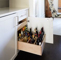 an open drawer in the middle of a kitchen filled with bottles and wineglasses